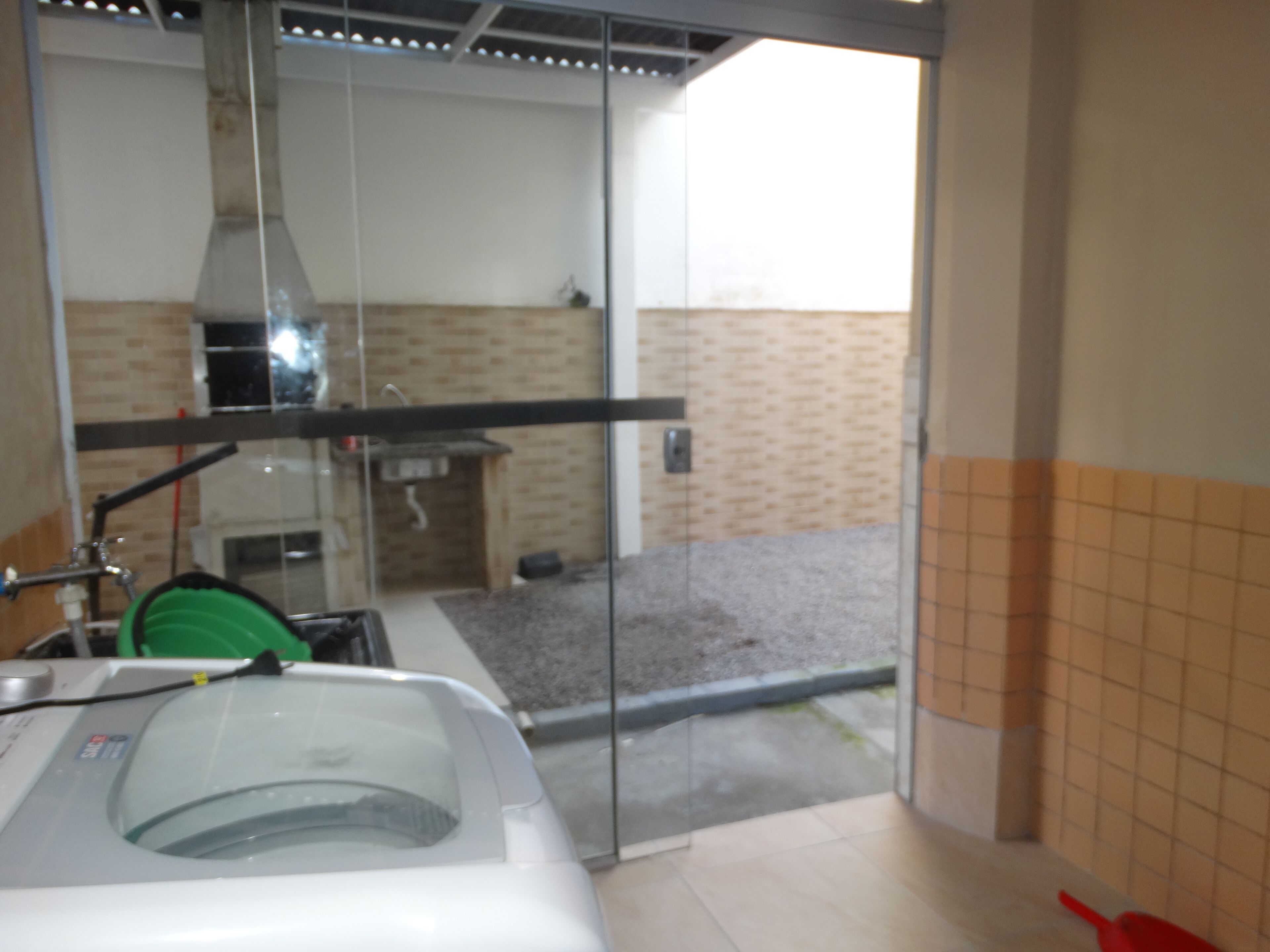 A bathroom with a glass shower enclosure, a sink, and a visible outdoor area with a tiled wall.