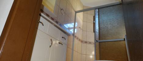 A bathroom with a toilet, a shower, and a sink.