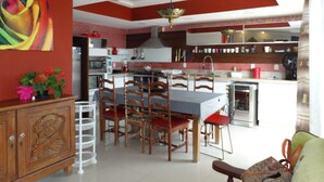 A modern kitchen with red and white color scheme, wooden cabinets, and a dining area with chairs. - House on the Sand - 219 (Florianópolis)