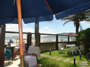 Un espace extérieur aménagé avec des tables et des chaises, une vue sur la plage et un palmier.