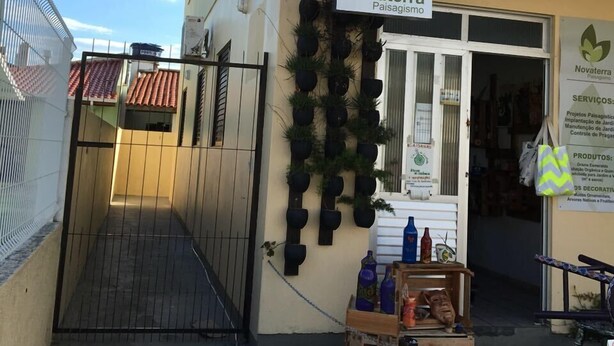 A storefront with a sign reading "Novaterra Paisagismo" and a display of potted plants. - Apartment 1D, 50m From the Sea - 65 (Florianópolis)