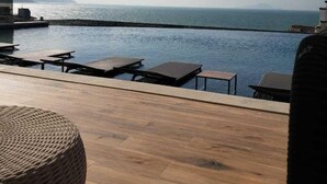 A wooden deck with lounge chairs and a pool overlooking the sea. - Apartment with Infinity Pool & Panoramic Views - 228 (Florianópolis)