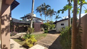 A residential area with a paved pathway, a small garden with plants, and a house with a sloped roof. - Large Pool House in Campeche - 109 (Florianópolis)