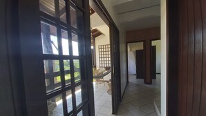 A hallway with a tiled floor leading to a room with a bed and a hammock. - Large Pool House in Campeche - 109 (Florianópolis)