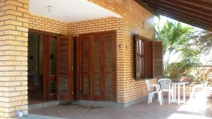 Ein überdachter Patio-Bereich mit Backsteinwand, Holzläden und Gartenmöbeln.