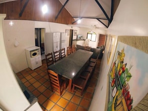 Een compacte keuken met een eethoek, voorzien van een betegelde vloer, een koelkast, een magnetron en een schilderij van fruit aan de muur.