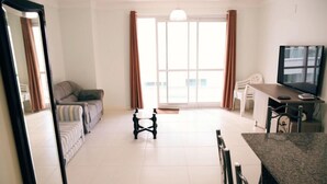 A living room with a sofa, a coffee table, a TV, and a dining area with chairs and a table. - 2 Bedroom Apartment - 201 (Florianópolis)
