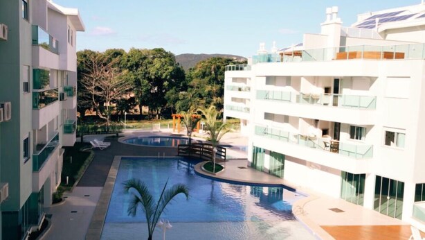 A modern hotel with a swimming pool, outdoor seating, and a view of the surrounding greenery. - 2 Bedroom Apartment - 201 (Florianópolis)