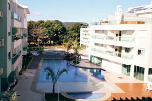 A modern hotel with a swimming pool, outdoor seating, and a view of the surrounding greenery.