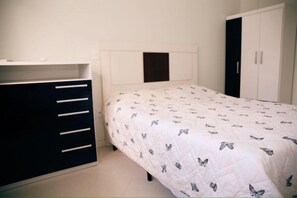 A bedroom with a bed, a wardrobe, and a desk.
