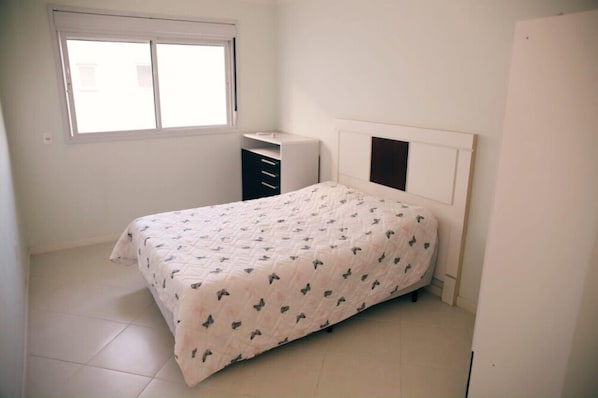 A bedroom with a bed, a dresser, and a window.