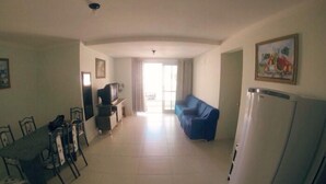 A spacious living area with a dining table and chairs, a sofa, a television, and a refrigerator. - 2 Bedroom Apartment - 202 (Florianópolis)