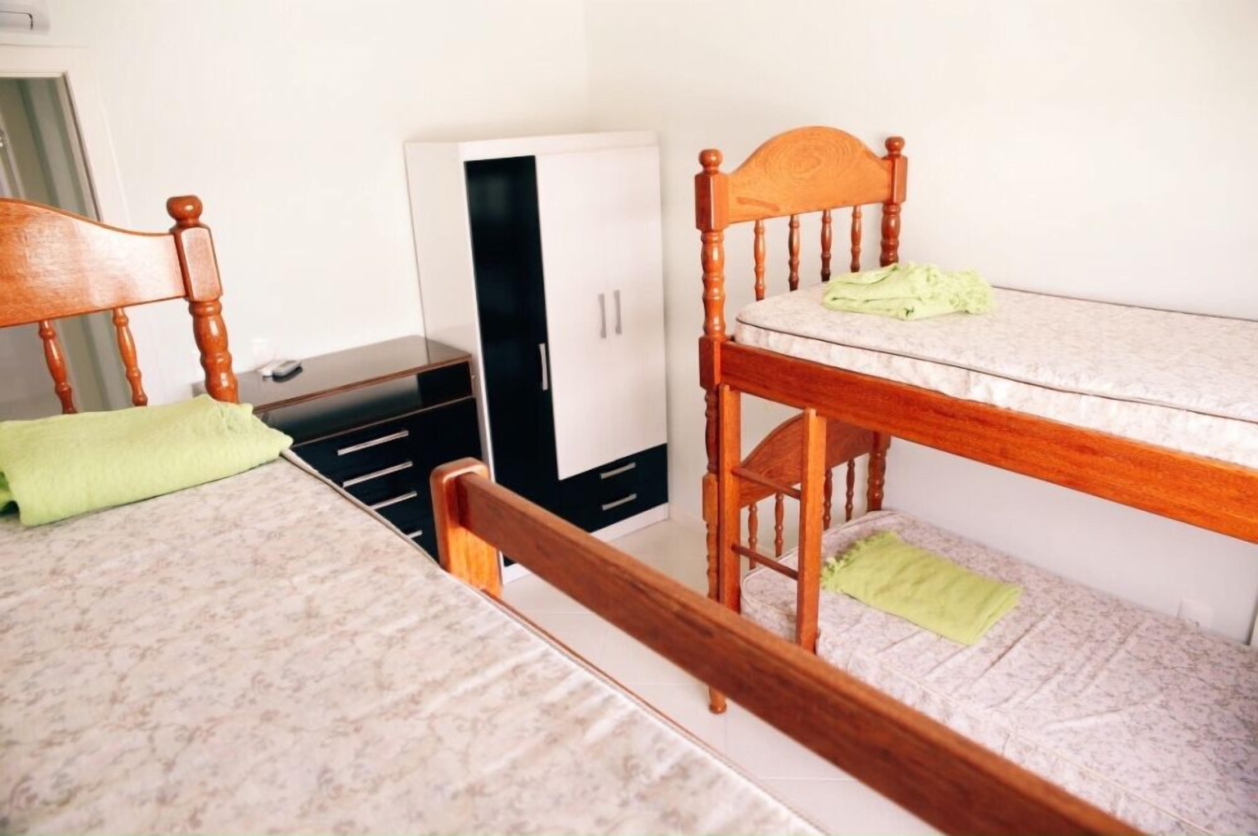 A bedroom with two bunk beds, a wardrobe, and a desk.