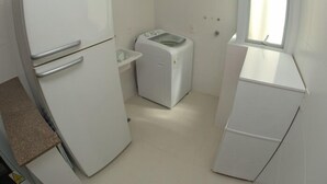 Eine kleine Küche mit Kühlschrank, Waschmaschine und Fenster.