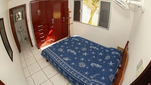Een slaapkamer met een bed, een kledingkast en een raam met zonwering.