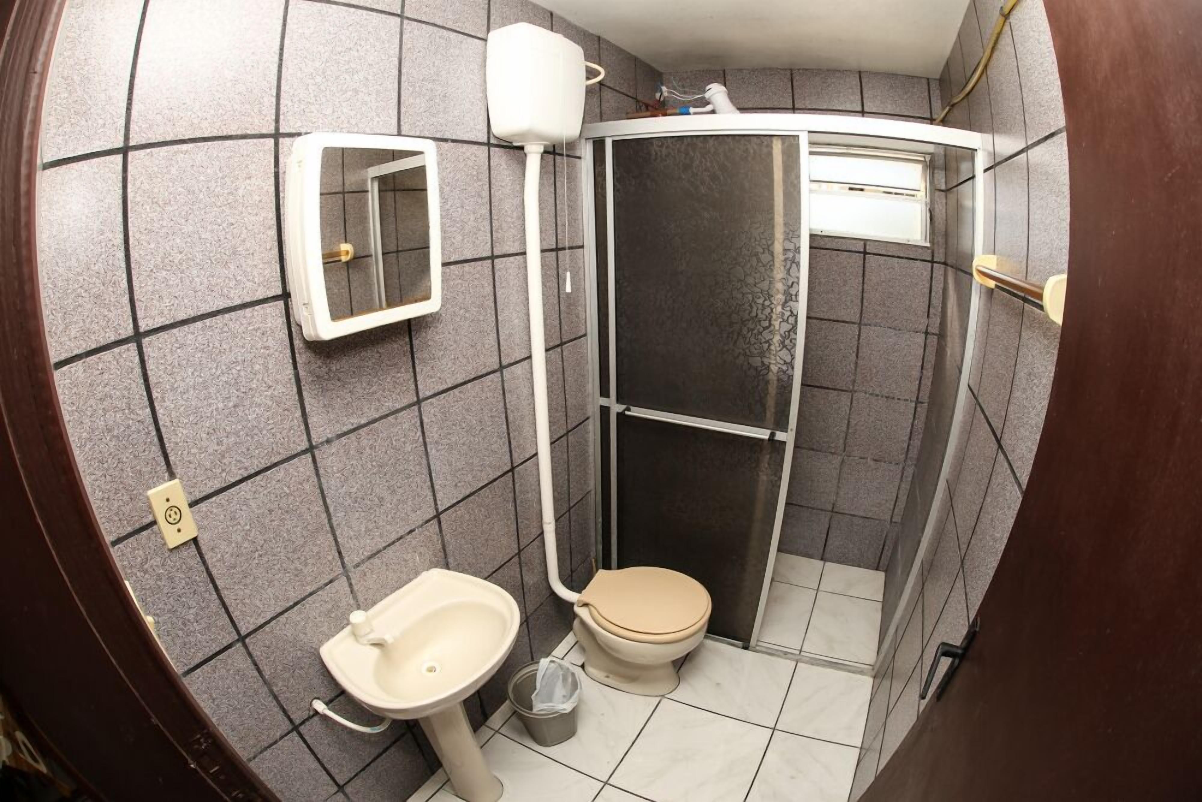 A compact bathroom with a toilet, sink, and shower stall.