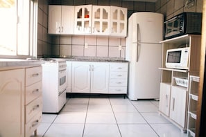 A kitchen with white cabinets, a refrigerator, a microwave, and a dishwasher.