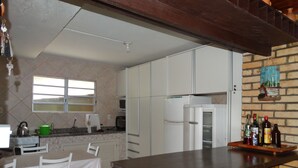 Una cocina con armarios blancos, un refrigerador, una estufa y una mesa de comedor con sillas.