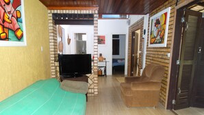 Una habitación con una cama, televisor, sofá y una puerta que da a otra habitación.