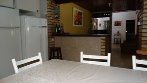 Una cocina con comedor, un refrigerador, una barra con botellas y un cuadro en la pared.