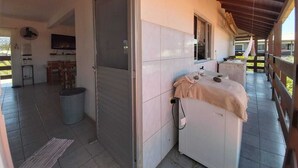 Una habitación con piso de baldosas, una cama con cubierta color beige, techo de madera y una ventana.
