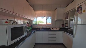 Cocina compacta con armarios blancos, encimera negra, microondas, fregadero y refrigerador.
