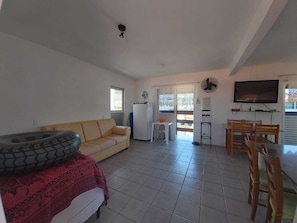 Una sala de estar con sofá, una mesa de comedor con sillas, televisor y refrigerador.