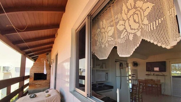 Un balcón con techo de madera, una cortina de encaje blanco y vistas a una cocina y comedor.