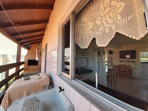 Un balcón con techo de madera, una cortina de encaje blanco y vistas a una cocina y comedor.