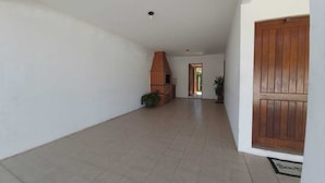 Un pasillo con suelo de baldosas, chimenea de ladrillo y puerta de madera.