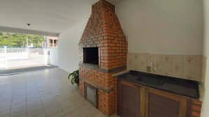 Una cocina exterior de ladrillo con horno integrado, fregadero y salpicadero de azulejos.