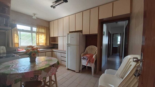 Una cocina con una mesa de comedor, sillas, un refrigerador y una butaca con una manta.