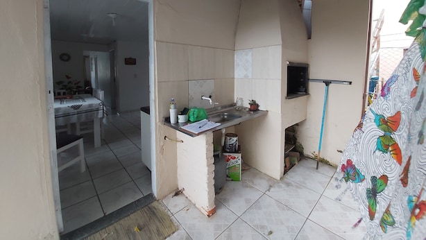 A compact kitchen with a tiled backsplash, a small sink, and a window overlooking a balcony. - Casa Pé na Areia, 2D, C Ar - Ingleses 41 (Florianópolis)