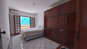 Une chambre à coucher avec un lit, une armoire et une fenêtre donnant sur des palmiers.