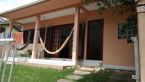 Una casa con porche, una hamaca y un tendedero.