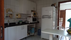 Una cocina con armarios blancos, microondas, refrigerador y una mesa de comedor con sillas.