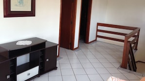 Una habitación con un banco de madera, un aparador de madera oscura y un cuadro en la pared.
