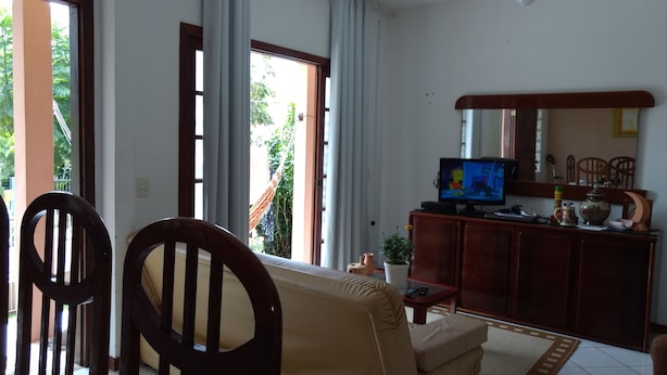 Una sala de estar con sofá, sillas, televisor y aparador.