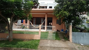 Una casa residencial con entrada protegida por un portón, una escalera que lleva a la puerta principal y un pequeño jardín.