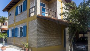 Un bâtiment à deux étages avec une façade jaune, des volets bleus et un balcon bien visible.