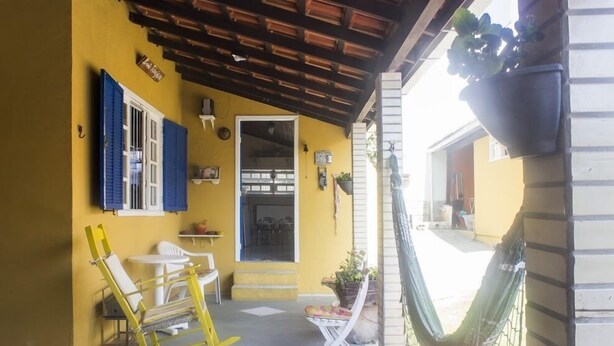 Un bâtiment jaune doté d’un porche abrité, d’un hamac et de sièges d’extérieur.