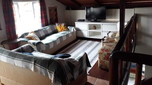 Un salon confortable avec un canapé, un téléviseur et un plafond en bois.