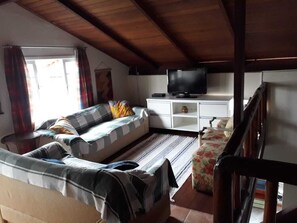Uma sala de estar aconchegante com sofá, televisão e teto de madeira.