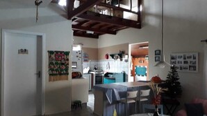 Un vaste espace de vie comprenant un coin cuisine à l’arrière-plan, une table à manger avec des chaises et un escalier menant à l’étage supérieur.