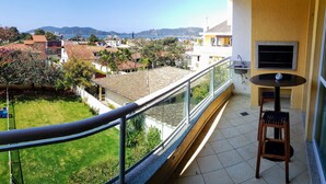 A balcony with a view of a residential area, a small table with a chair, and a built-in sink. - Ap Premium na Lagoa (Florianópolis)