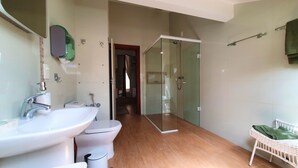 Un baño moderno con cabina de ducha de vidrio, un lavabo blanco y un inodoro.