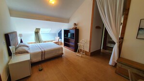 Un dormitorio con una cama, televisor, escritorio y una silla.