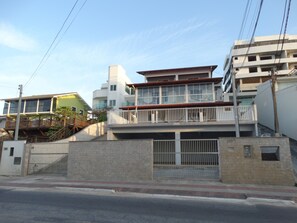 A multi-story residential building with a balcony, a gated entrance, and a staircase leading to the upper floors. - Apartment with Terrace & Sea View - 61 (Florianópolis)