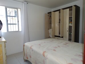 A bedroom with a bed, a wardrobe, and a window with curtains. - Apartment with Terrace & Sea View - 61 (Florianópolis)