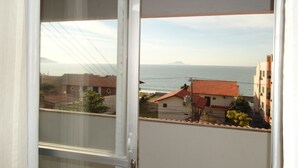 Uitzicht vanaf een balkon, met zee en gebouwen op de achtergrond.